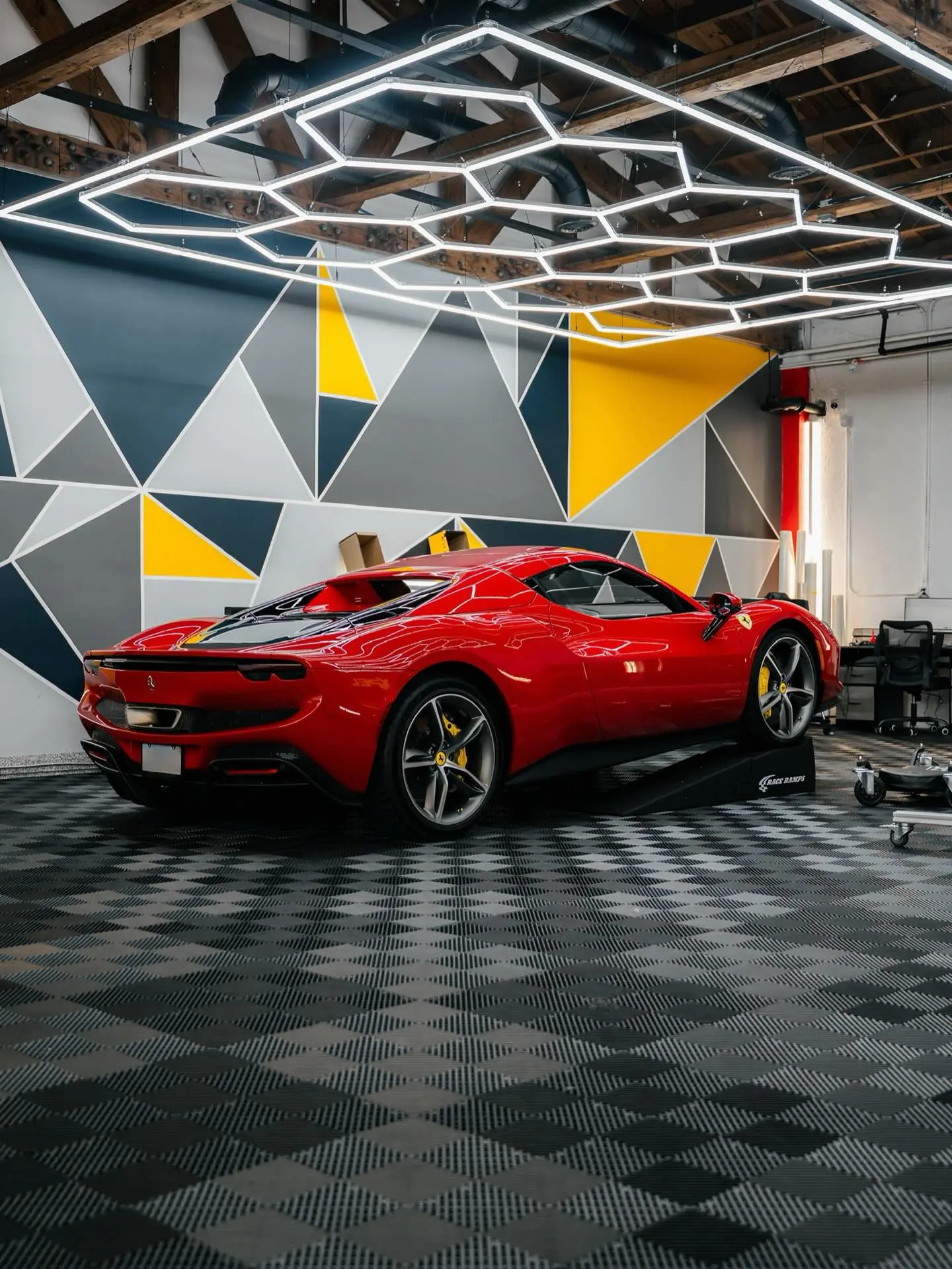 Red Ferrari 296 parked on the geometric-walled floor of the Rides Miami facility