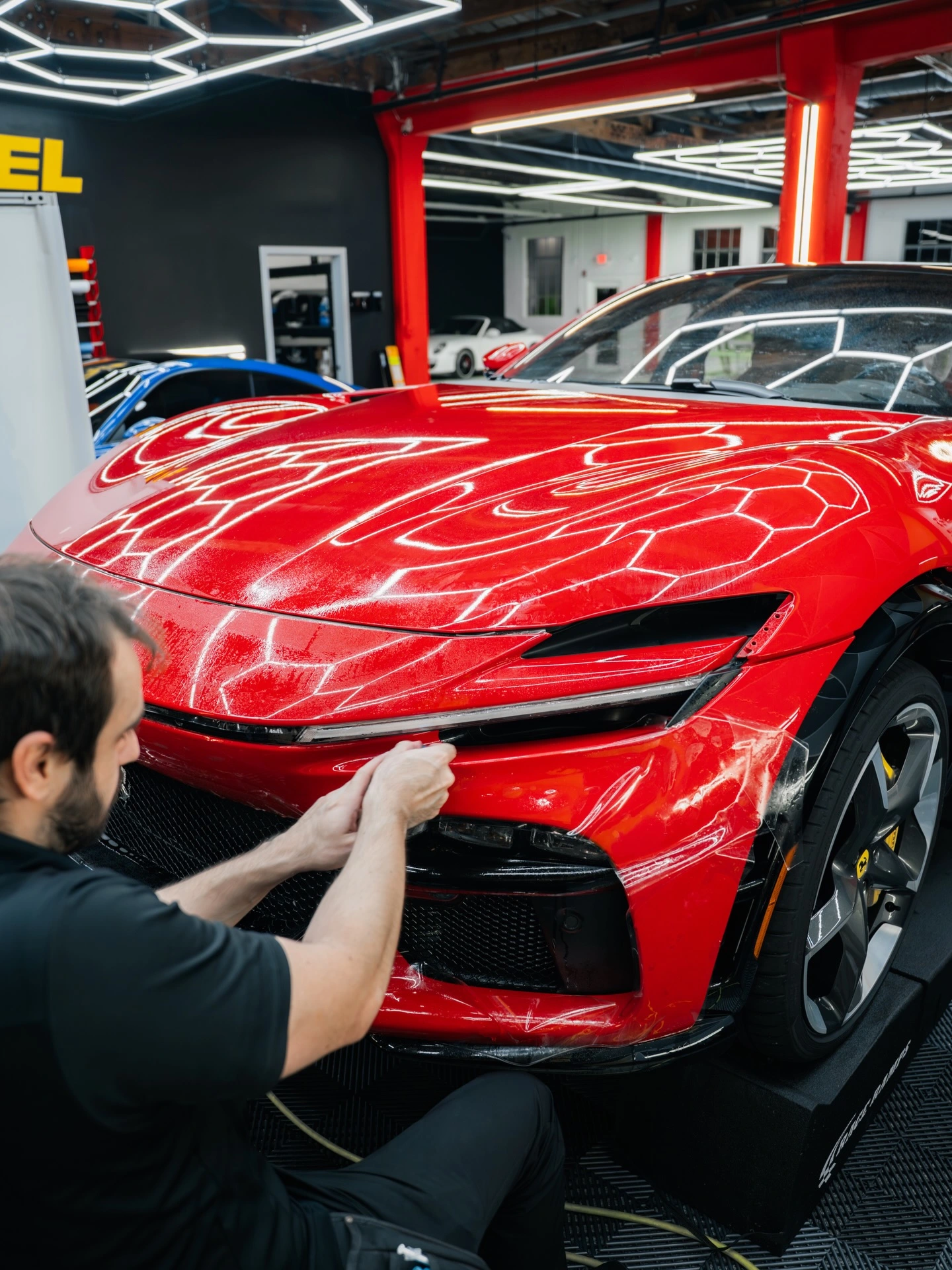 Rides Miami installer applying XPEL paint protection film to the front bumper of a red Ferrari