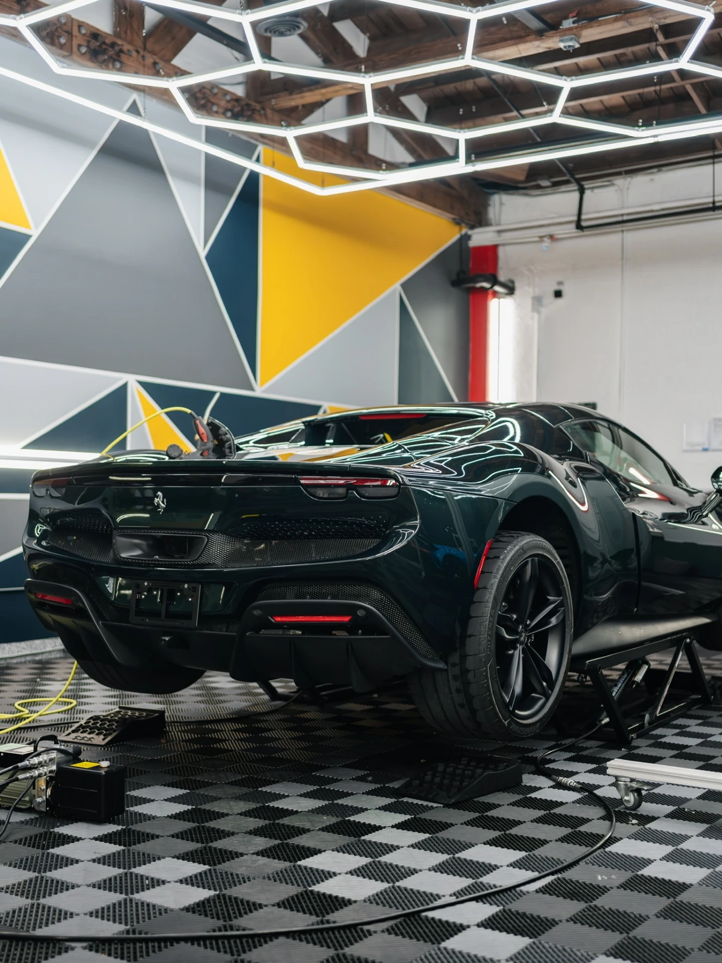 Dark green Ferrari raised on stands inside the Rides Miami climate-controlled bay